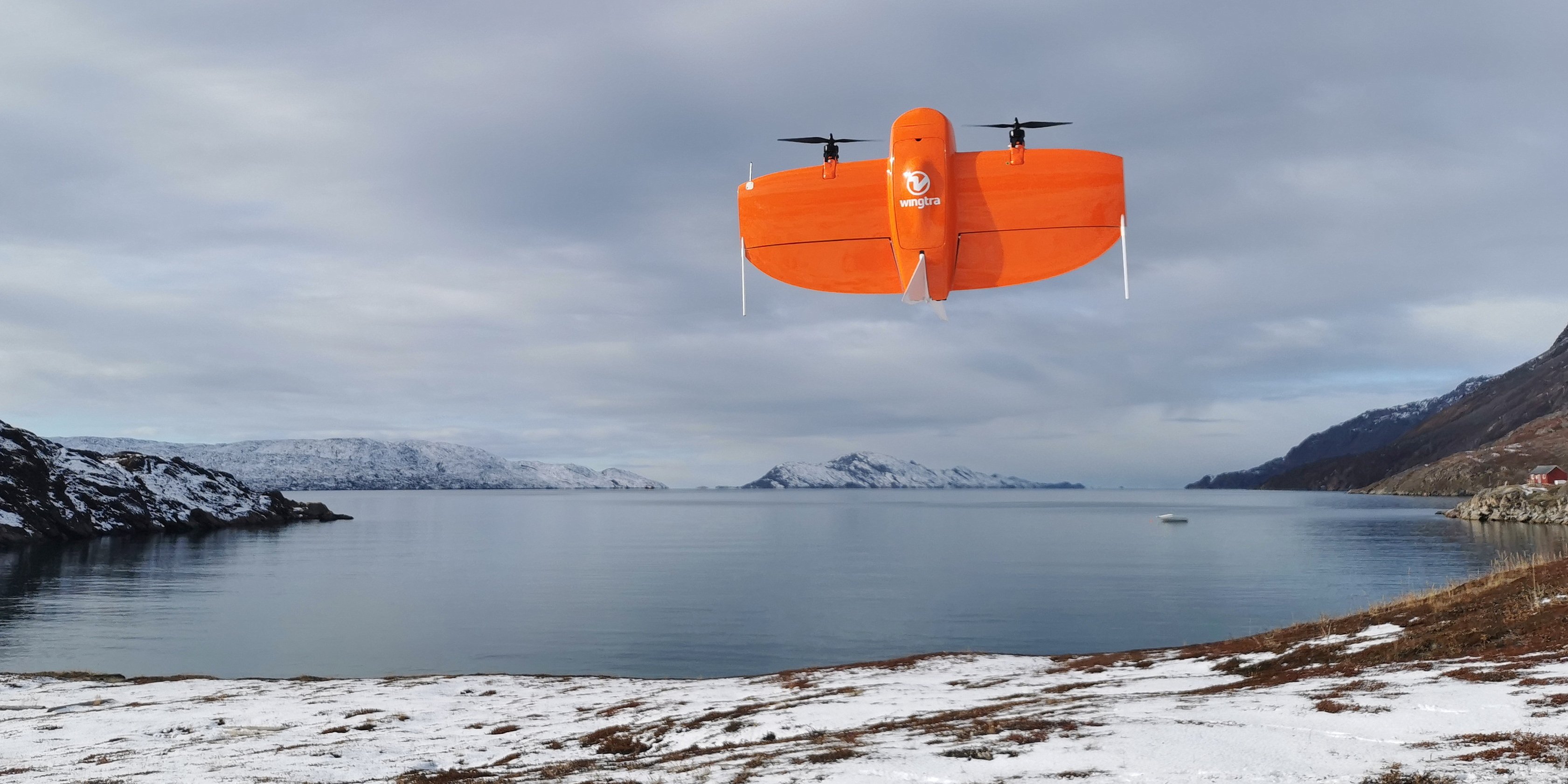 Eine rote Drohne startet vor einer Meeresbucht in der Arktis.