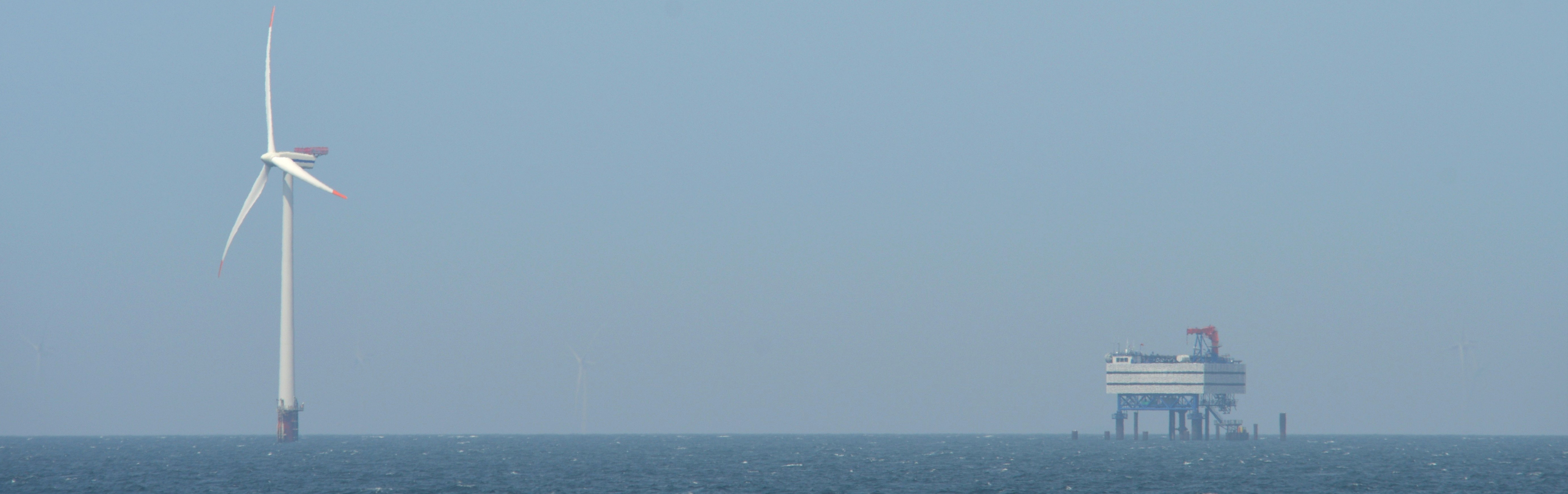 Eine Offshore-Windenergieanlage und eine Umspannplattform im Meer.